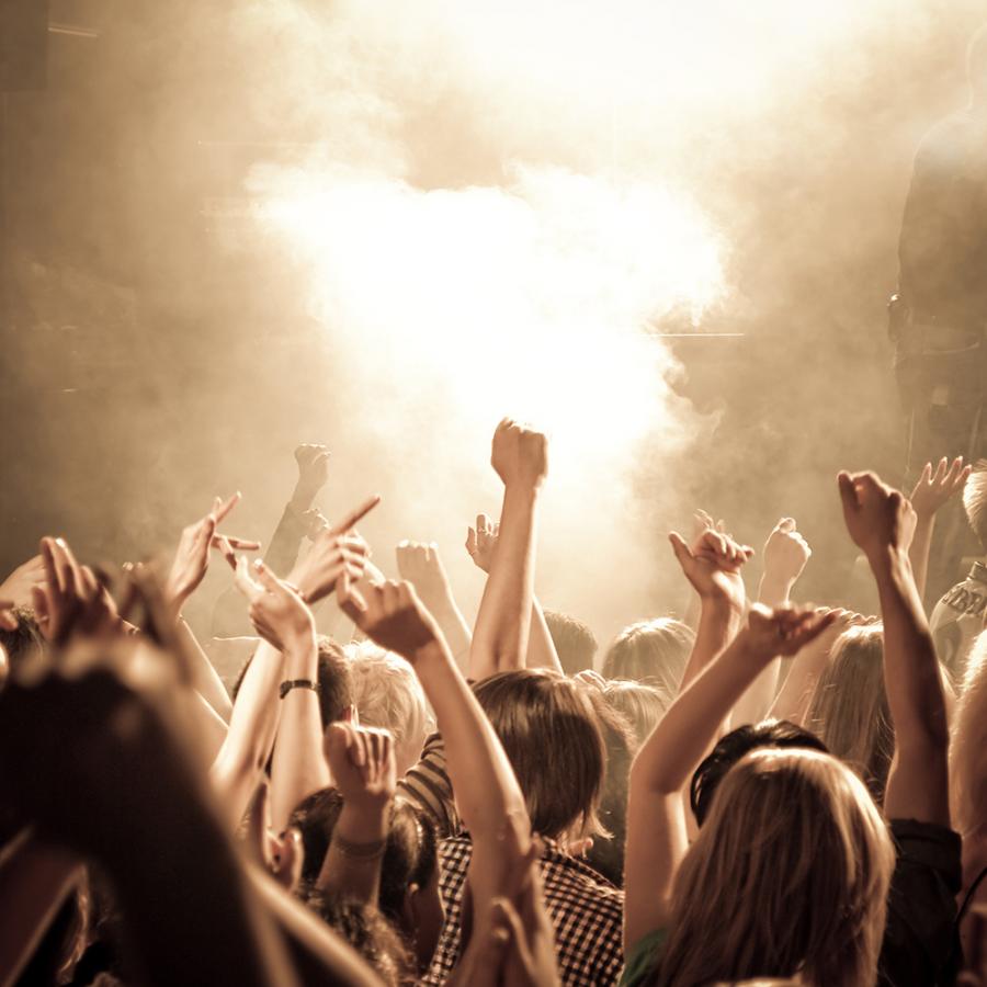 Pubblico esultante a un concerto con effetti di luce suggestivi.